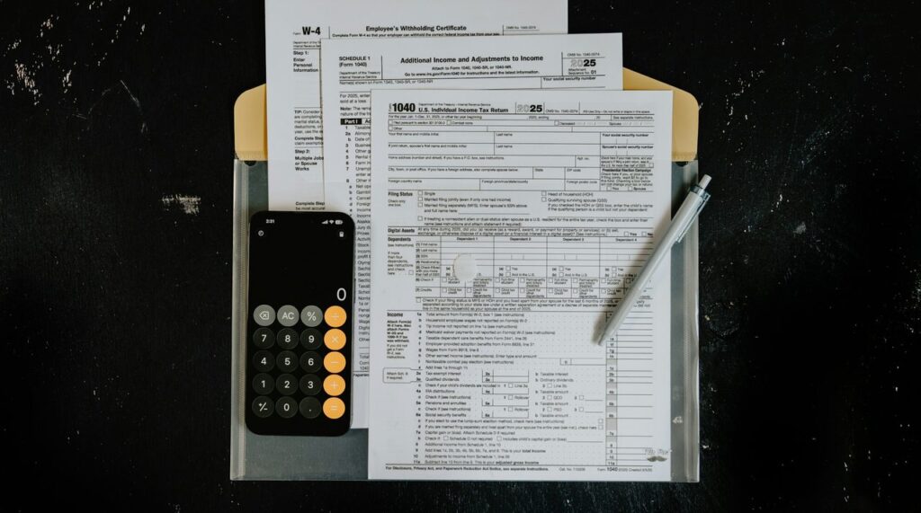 Federal tax forms with a calculator and pen on a dark desk