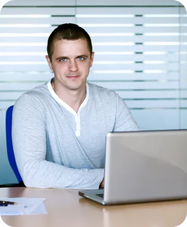 Smiling man working on a laptop in an office