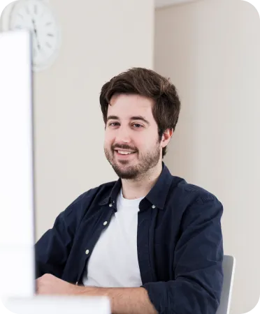 Smiling man in a dark jacket sitting at a desk